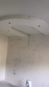 Teilrenovierter Raum mit abgehängter Deckenkonstruktion, eingebauten Lichtkörpern und sichtbarer Verkabelung