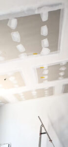 Gespachtelte Trockenbaudecke mit gelben Befestigungsankern, Spachtelfugen und Leiter vor der Wand