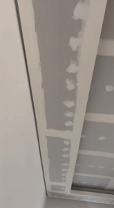 Decke mit weißer Gipskartonverkleidung, abgeklebten und verspachtelten Fugen, Vorbereitungen für Endbearbeitung