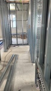 Baustellenraum mit Metallprofilrahmen, offenen Kabeln am Boden, Werkzeugen und Baumaterial im Hintergrund.