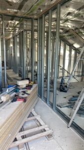 Baustellenraum mit Metallständerwänden, Dämmung, Werkzeugen, Holzplatten und Leiter während Renovierungsphase